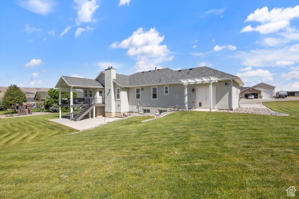 Back of property with a chimney, a lawn, stairs, and a pergola