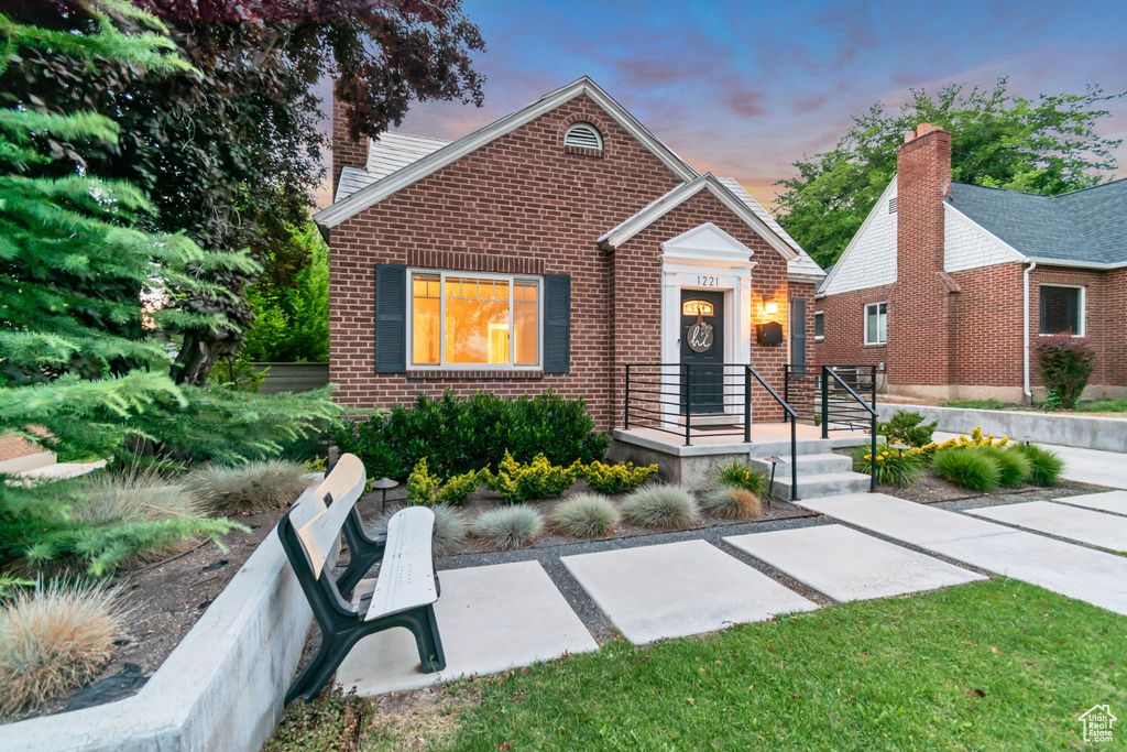 View of front of home featuring brick siding and a chimney