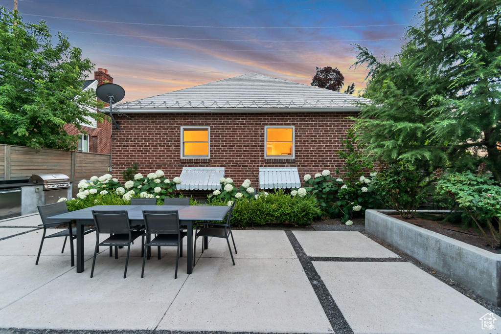 Patio terrace at dusk with outdoor dining space, area for grilling, and a patio area