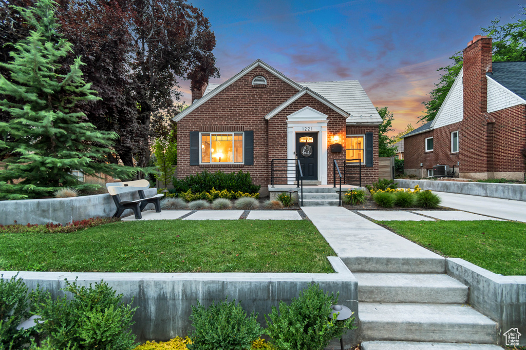 View of front of property featuring brick siding and a yard