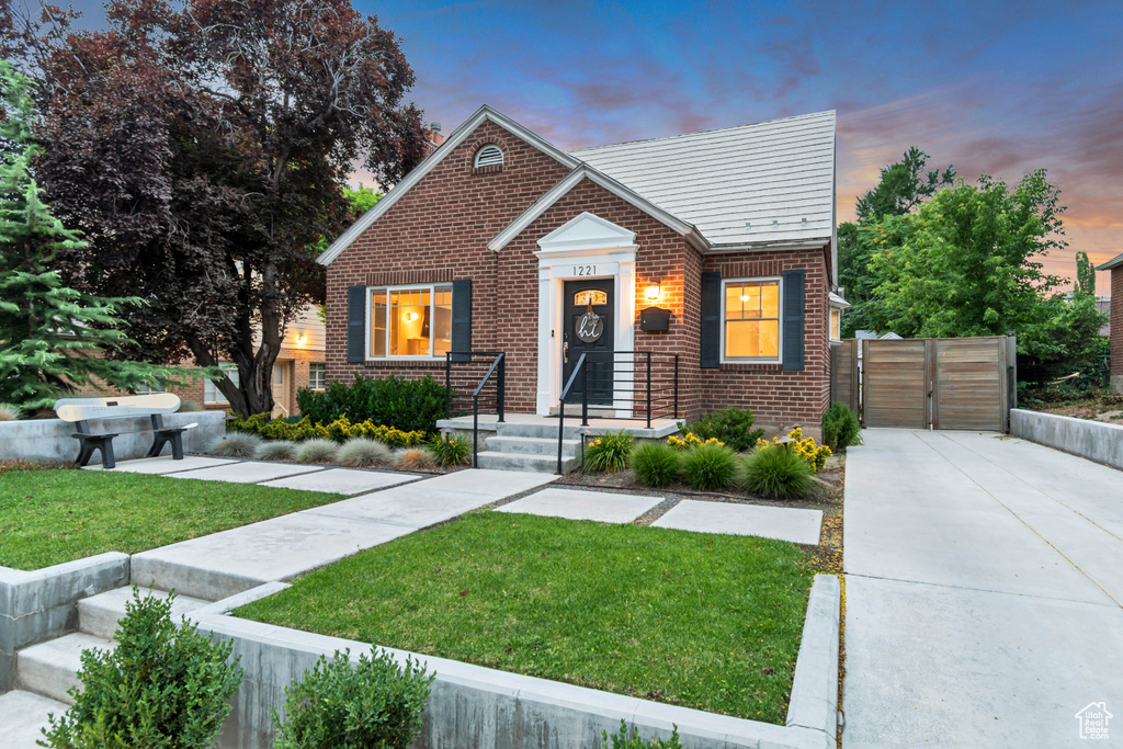 View of front of house with a front lawn, brick siding, and a gate