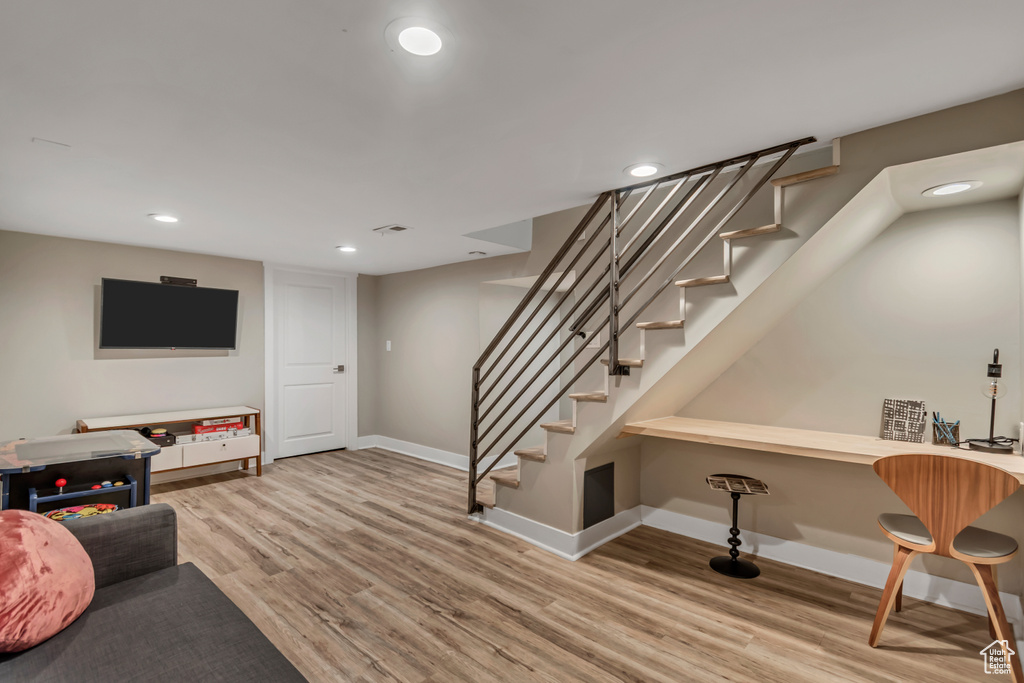 Living area with wood finished floors, recessed lighting, and stairs