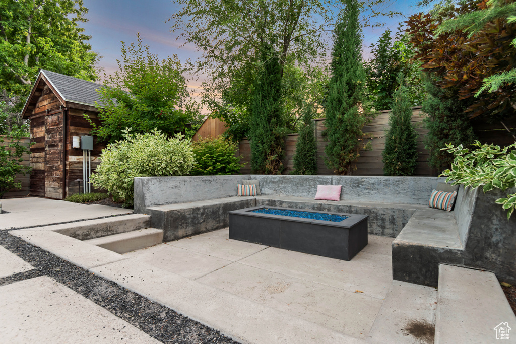 Patio terrace at dusk with a fire pit, a patio area, and a fenced backyard