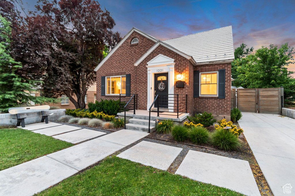 Bungalow-style home with brick siding and a gate