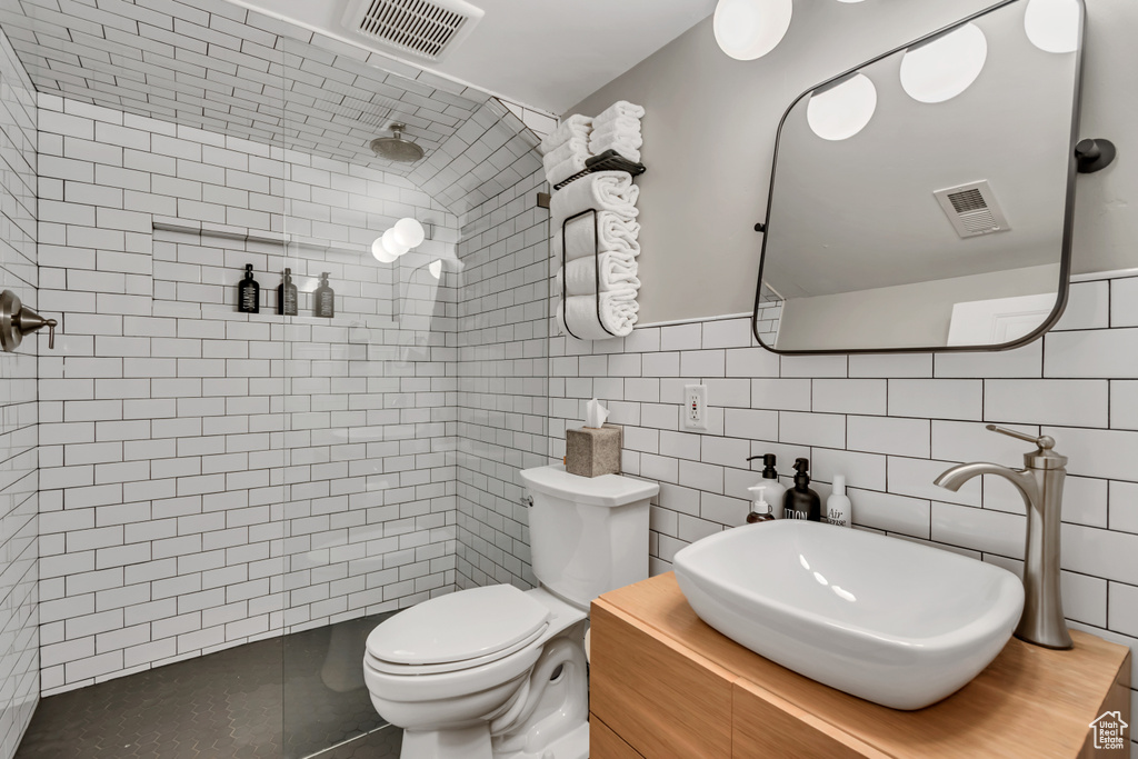 Bathroom featuring tiled shower, tile walls, and vanity