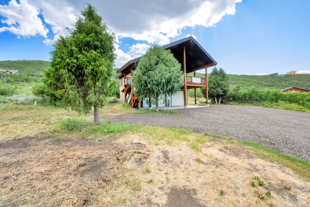 View of front of property featuring driveway, a wooden deck, and an attached garage