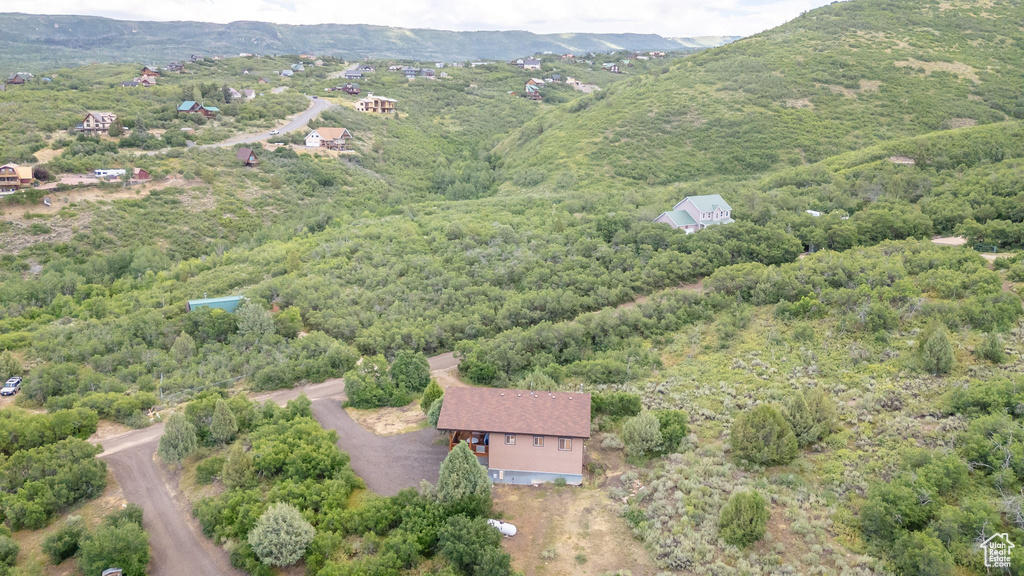 Aerial view of property and surrounding area featuring mountains and a heavily wooded area