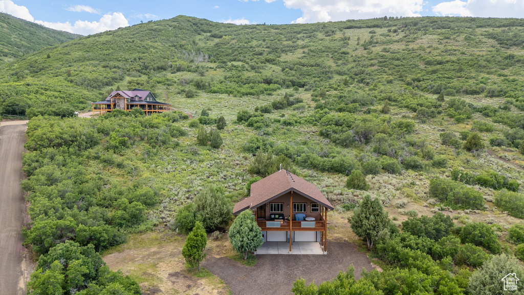 Aerial view of property and surrounding area featuring a mountainous background and a forest