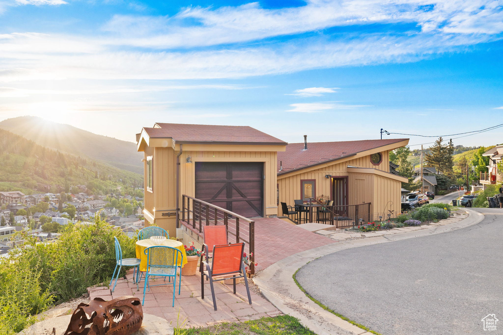 View of front facade with a mountain view, a patio area, and a garage