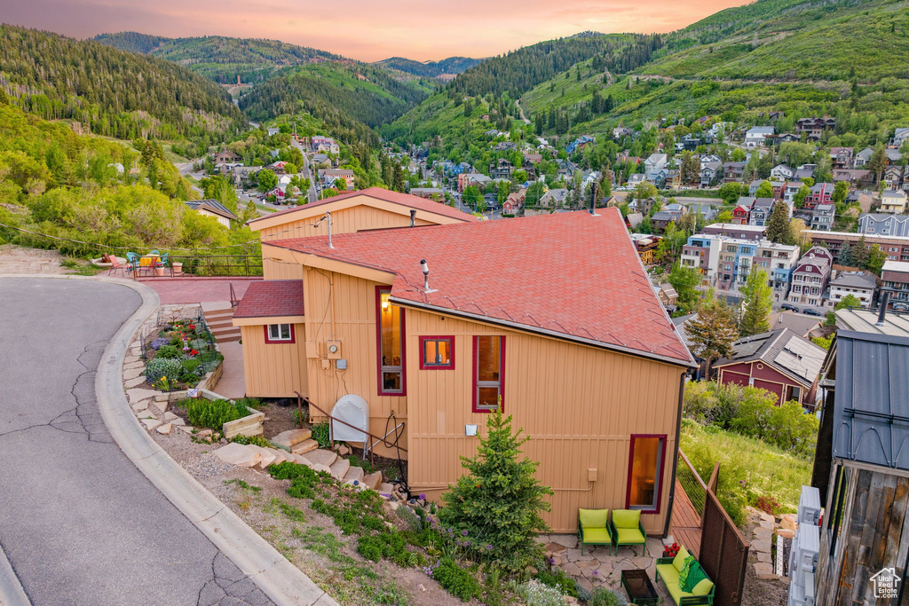 Property exterior at dusk with a mountain view and a shingled roof