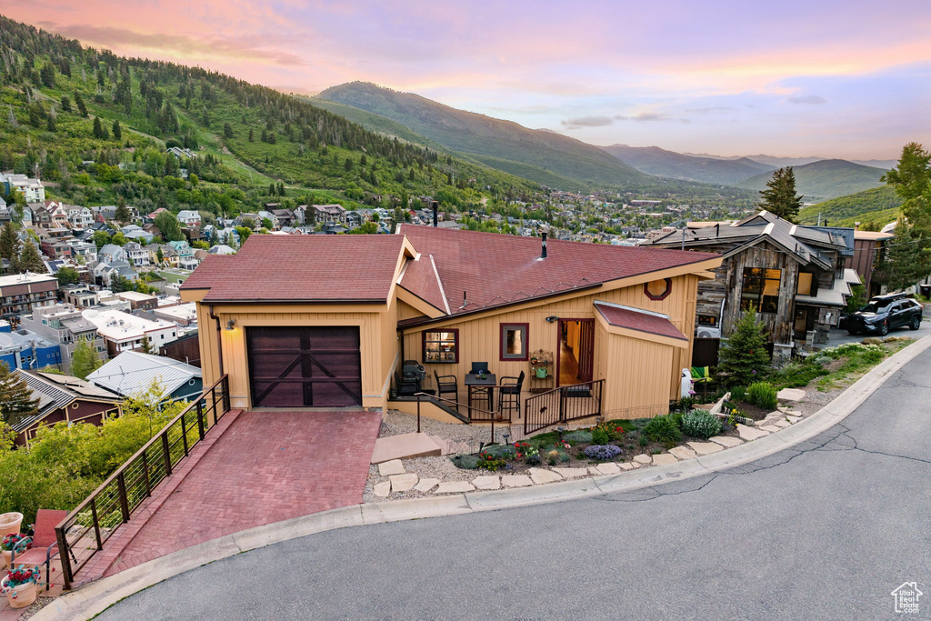 View of front of property featuring a mountain view, a garage, decorative driveway, and roof with shingles