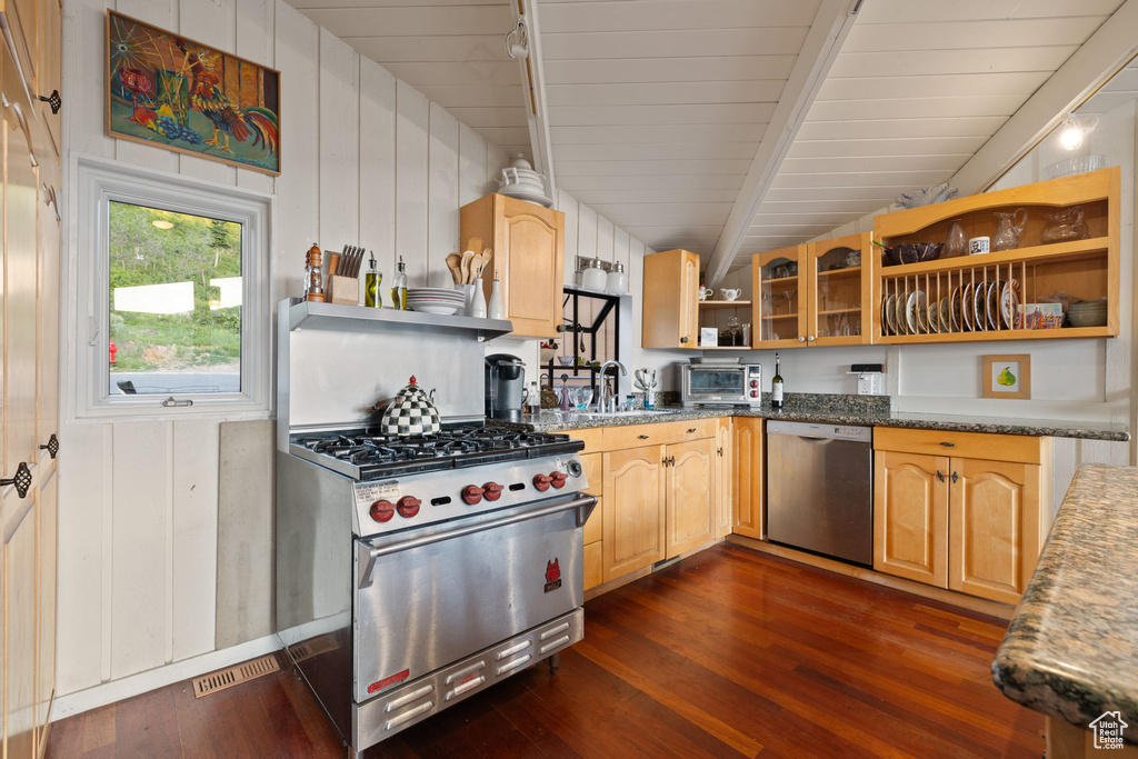 Kitchen featuring appliances with stainless steel finishes, open shelves, dark wood-type flooring, glass insert cabinets, and light brown cabinetry