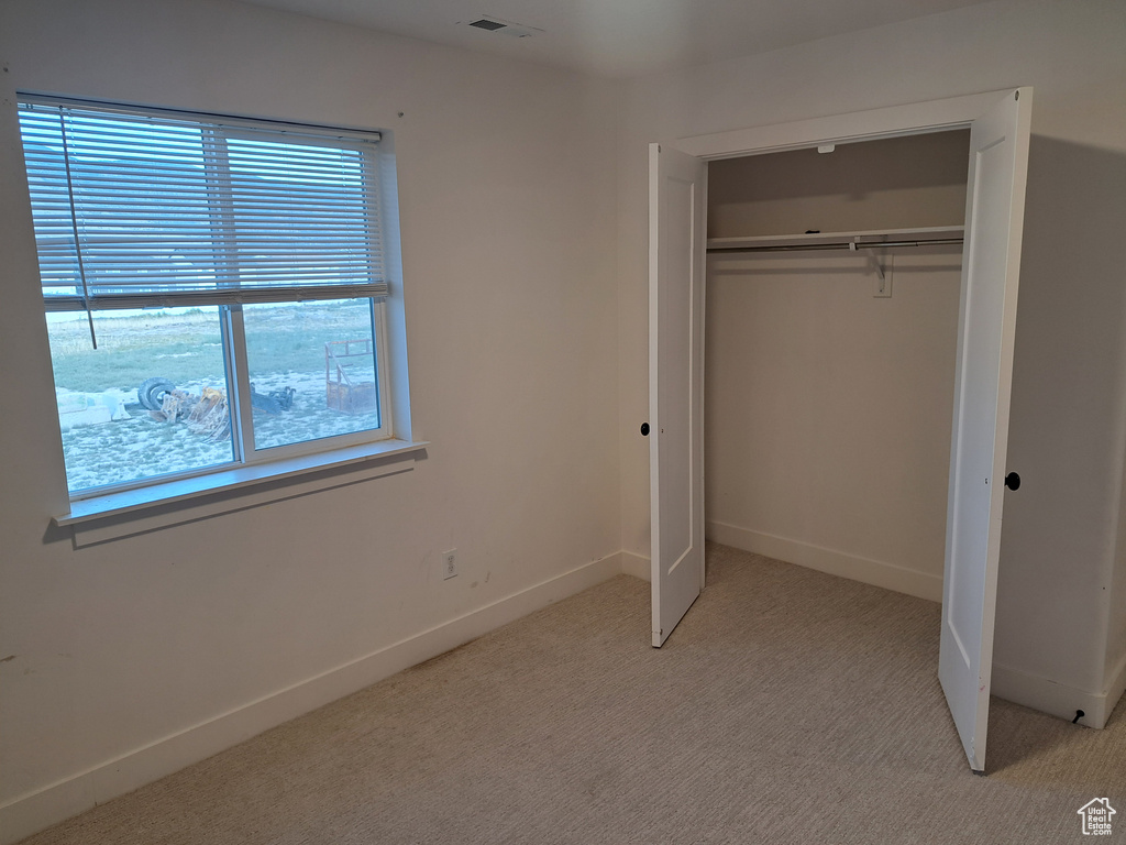 Unfurnished bedroom featuring light carpet and a closet