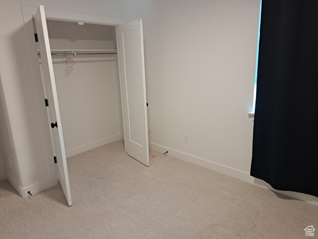 Unfurnished bedroom with light colored carpet and a closet
