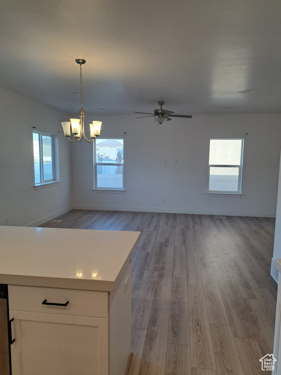 Unfurnished dining area with light wood-style flooring, a chandelier, and a ceiling fan