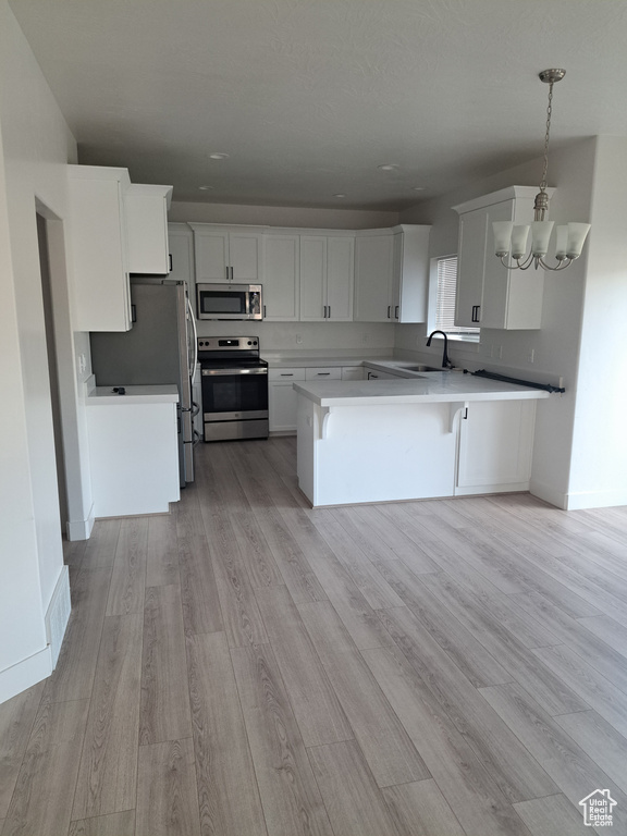 Kitchen featuring stainless steel appliances, light wood finished floors, white cabinets, and recessed lighting