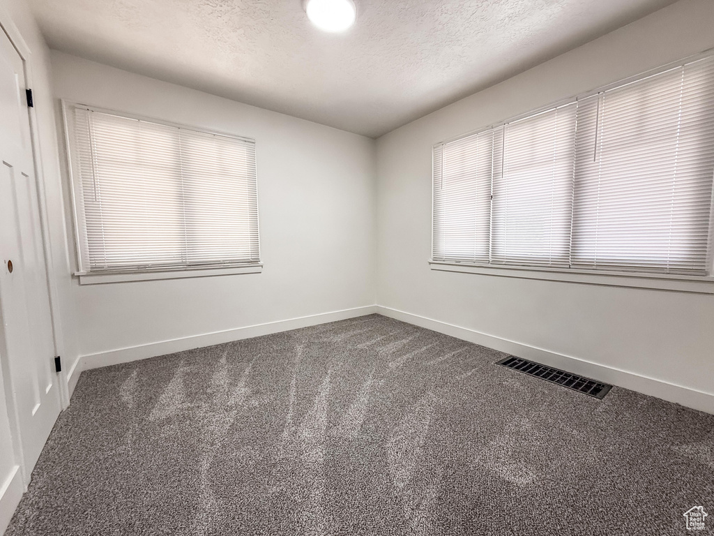 Spare room featuring dark colored carpet and a textured ceiling