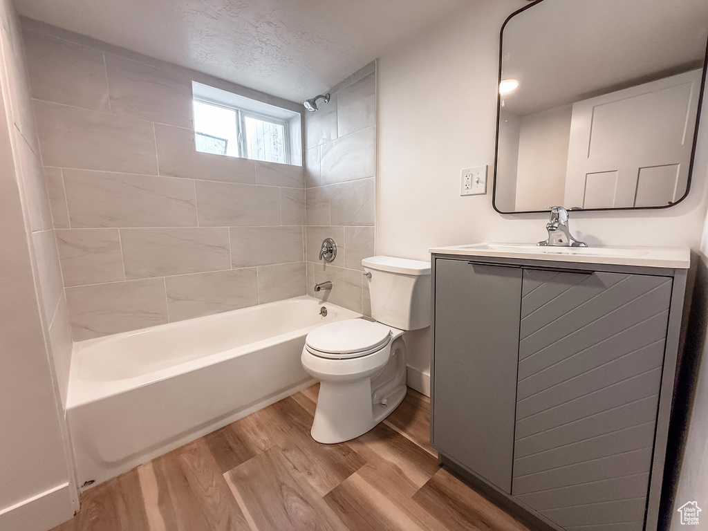 Bathroom with wood finished floors, vanity, bathtub / shower combination, and a textured ceiling