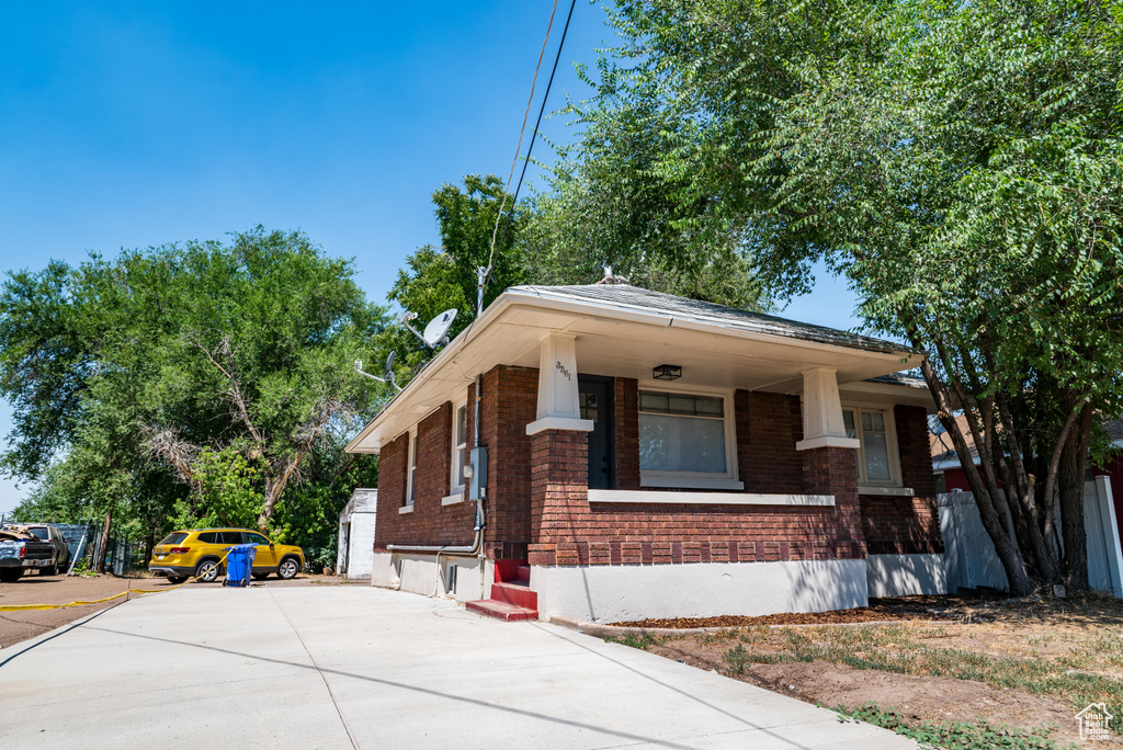 View of front of house featuring brick siding, concrete driveway, and covered porch
