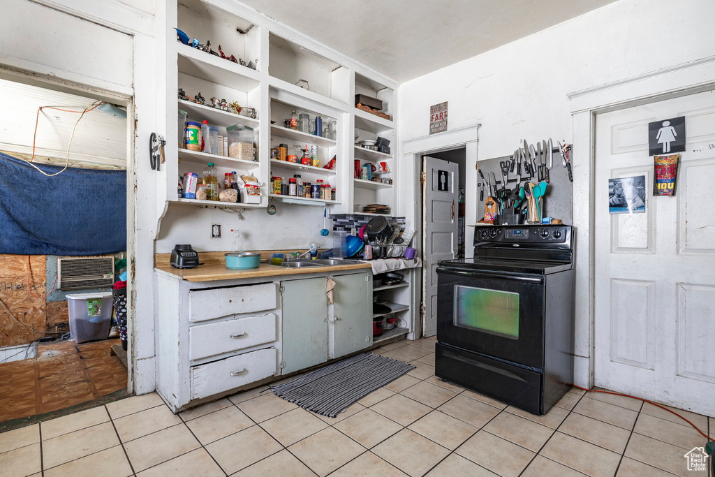 Kitchen with electric range, light tile patterned floors, open shelves, and light countertops