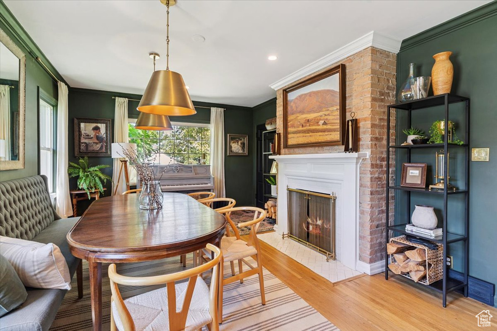Dining room with ornamental molding, light wood-type flooring, a lit fireplace, and recessed lighting