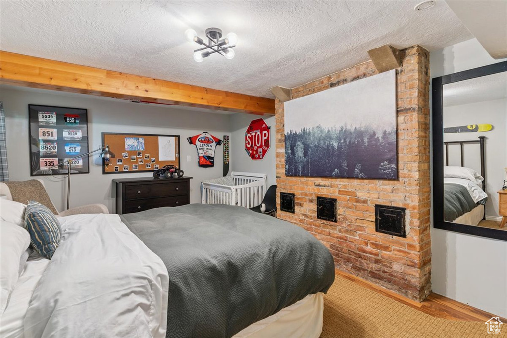Bedroom with a textured ceiling, wood finished floors, and beam ceiling