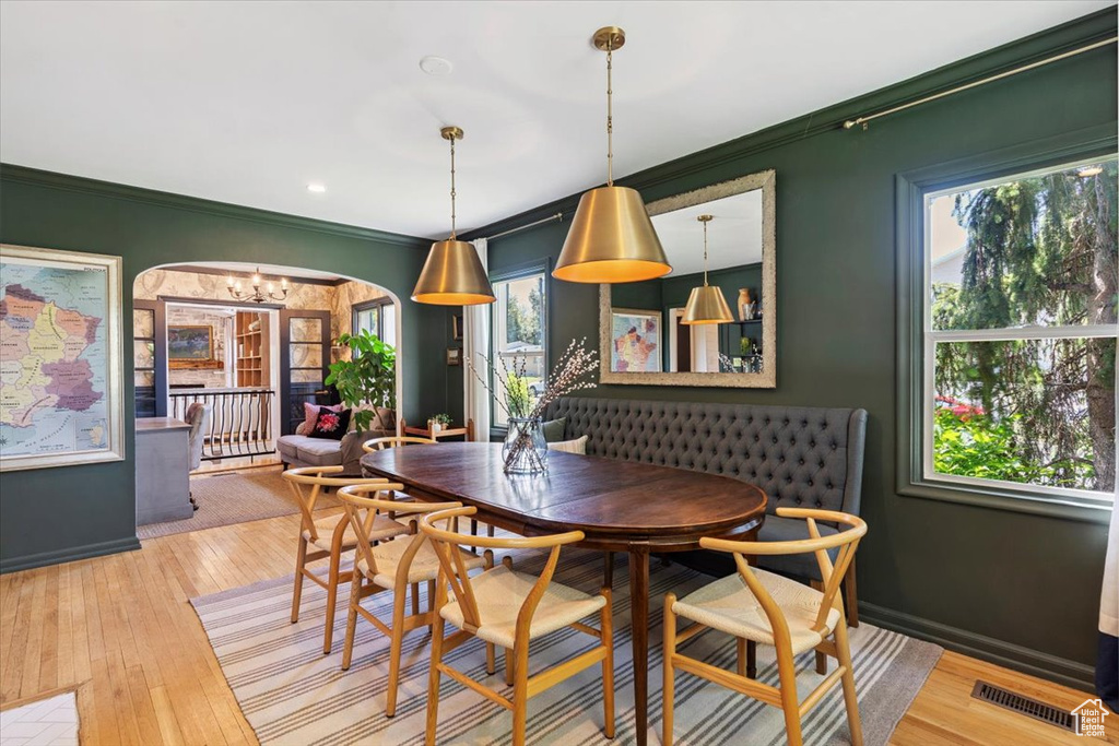 Dining area with arched walkways, ornamental molding, a chandelier, and hardwood / wood-style flooring