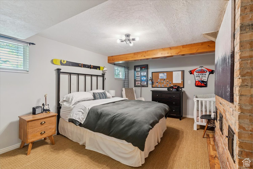 Bedroom featuring a textured ceiling, multiple windows, and light carpet
