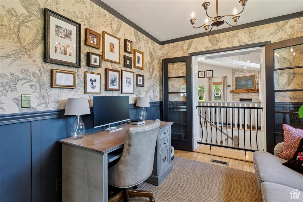 Office featuring wallpapered walls, a chandelier, wainscoting, wood finished floors, and crown molding