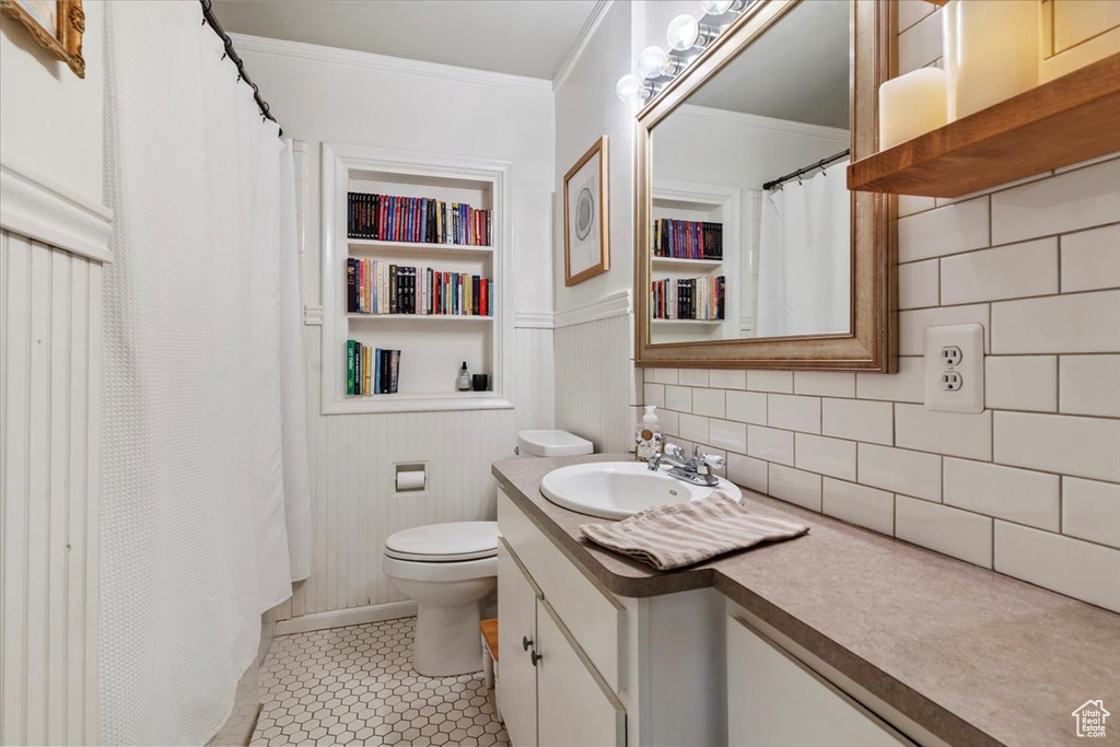 Full bathroom featuring vanity, crown molding, built in shelves, and decorative backsplash