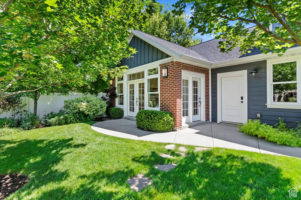 Entrance to property with french doors, board and batten siding, brick siding, and roof with shingles