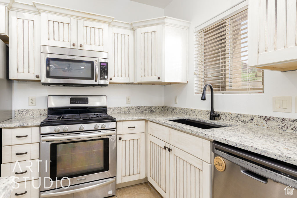 Kitchen with stainless steel appliances and light stone counters