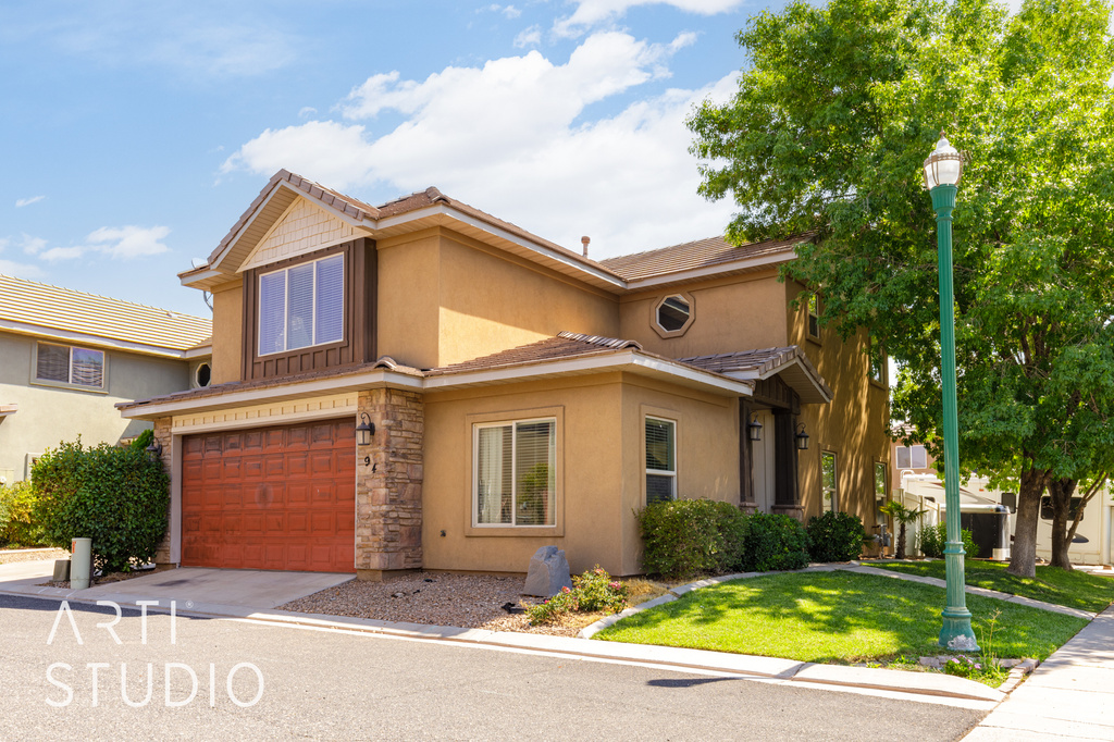 View of front of home featuring a garage, stucco siding, a front yard, stone siding, and driveway