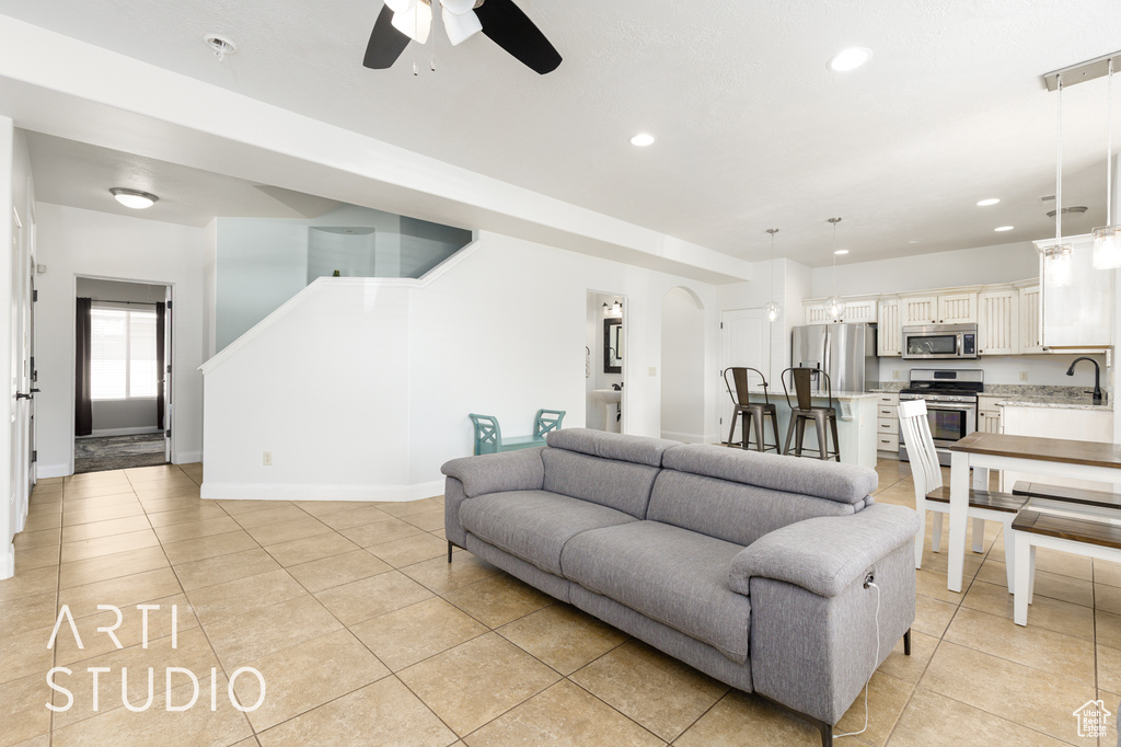 Living room with ceiling fan, light tile patterned flooring, and recessed lighting
