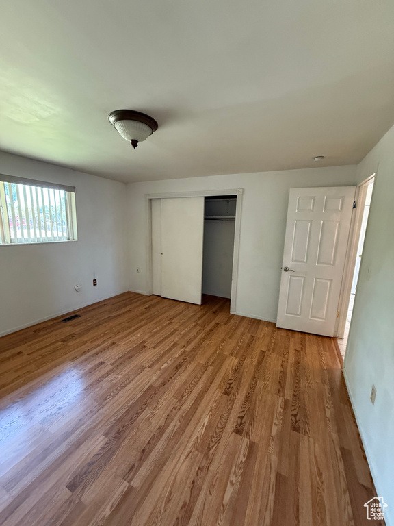 Unfurnished bedroom featuring light wood-style floors and a closet