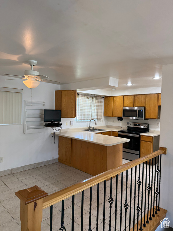 Kitchen with stainless steel appliances, brown cabinets, a peninsula, and light countertops