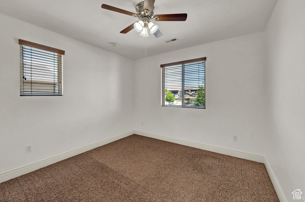 Carpeted spare room featuring baseboards and a ceiling fan