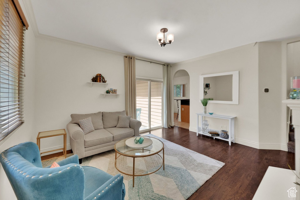 Living room with wood finished floors, crown molding, and a fireplace
