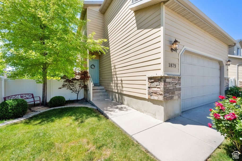 View of property exterior featuring stone siding, an attached garage, and entry steps