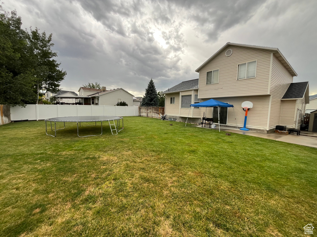 Fenced backyard with a trampoline and a patio area