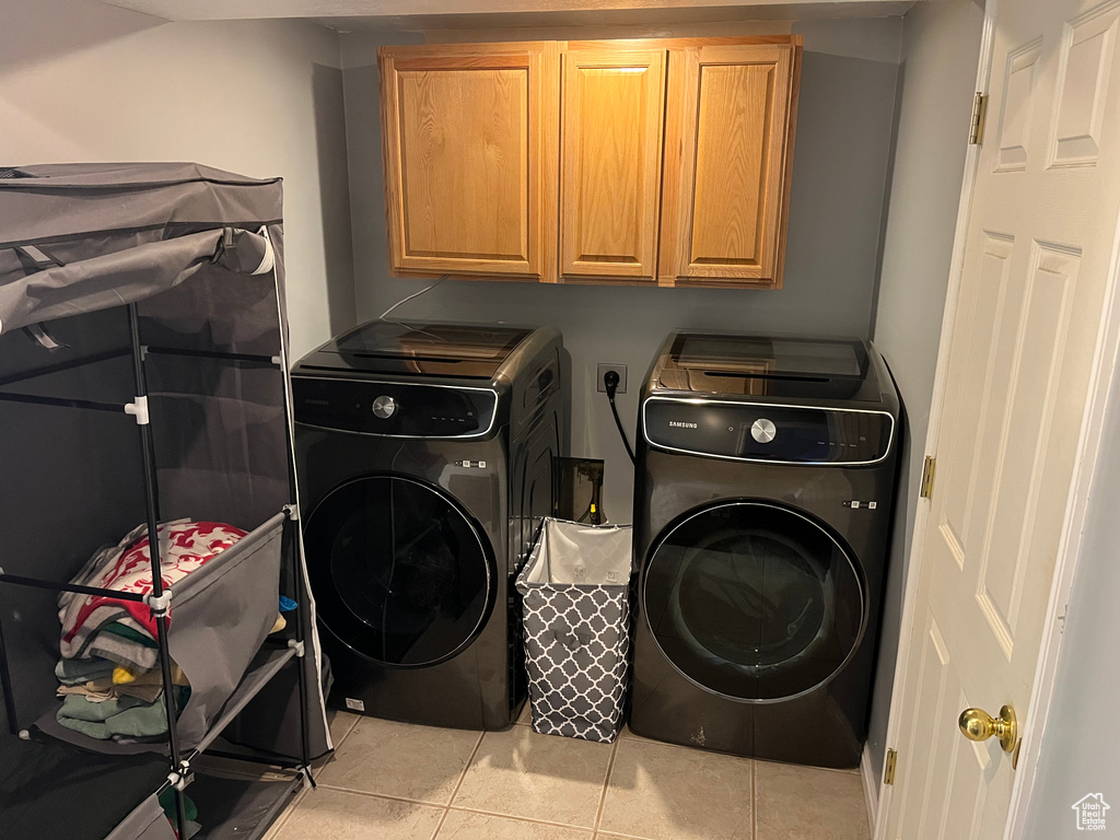 Washroom with cabinet space, light tile patterned flooring, and washer and dryer