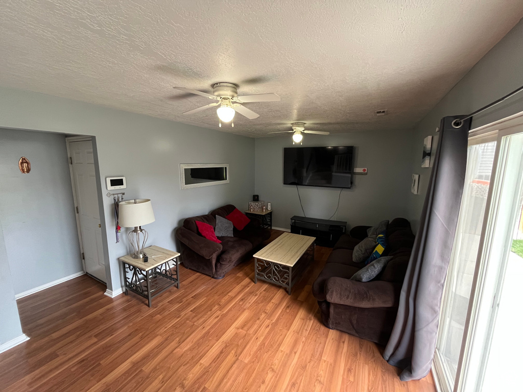 Living area featuring light wood-type flooring, a textured ceiling, and ceiling fan