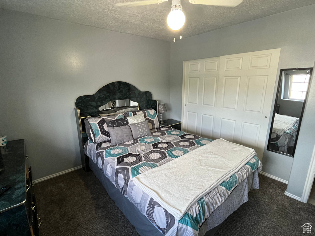 Bedroom with carpet floors, a textured ceiling, and ceiling fan