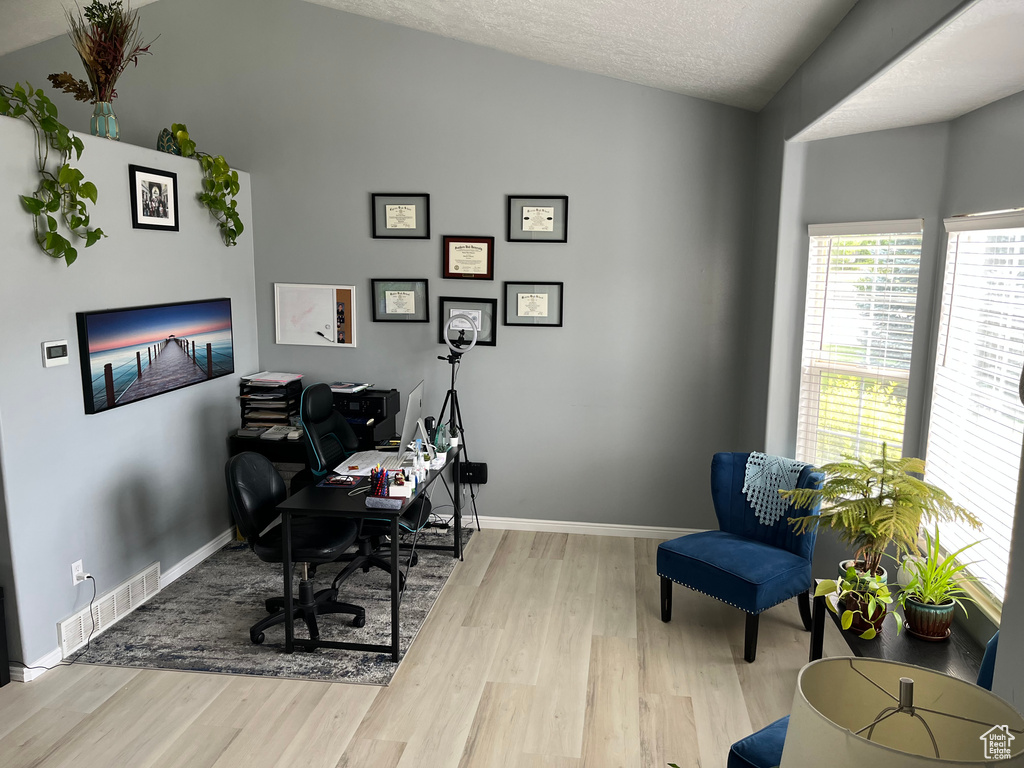 Office area featuring light wood-type flooring and a textured ceiling