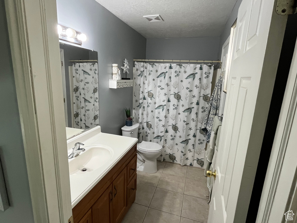 Bathroom featuring vanity, a textured ceiling, tile patterned flooring, and a shower with shower curtain