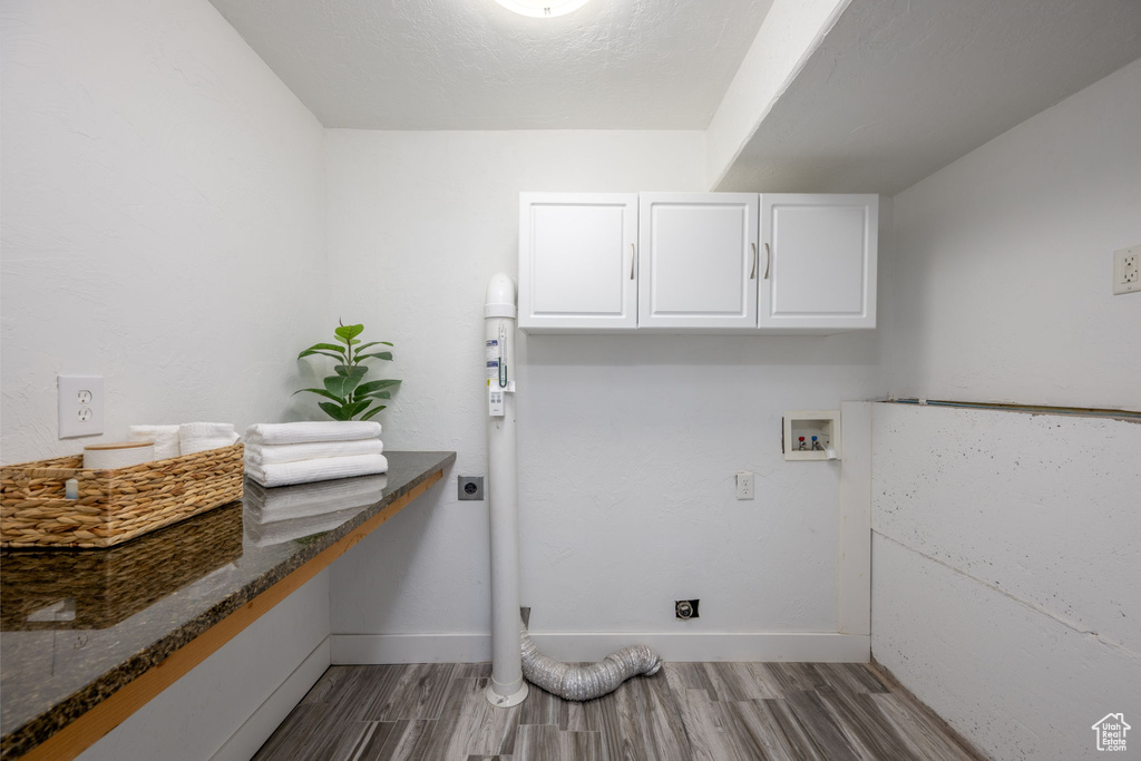 Laundry room with electric dryer hookup, cabinet space, wood finished floors, and washer hookup