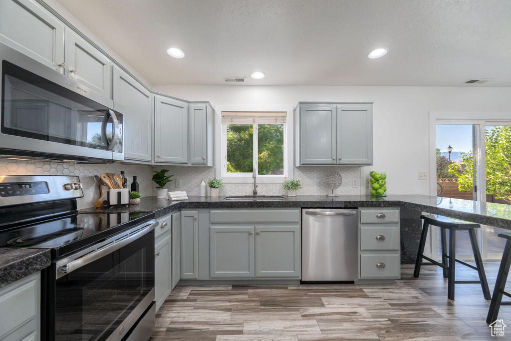 Kitchen with stainless steel appliances, healthy amount of natural light, tasteful backsplash, gray cabinets, and recessed lighting