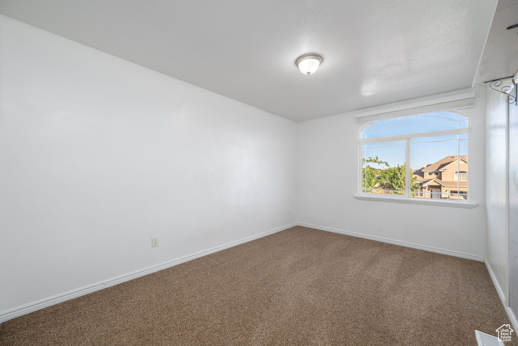 Carpeted spare room featuring baseboards