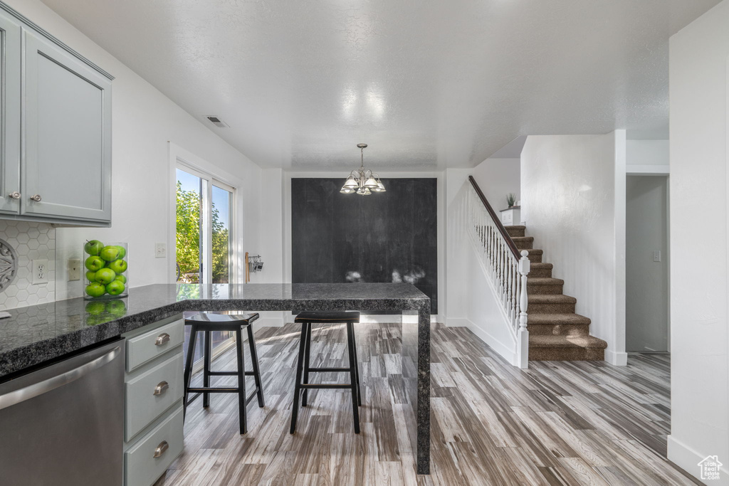 Kitchen featuring stainless steel dishwasher, light wood-style floors, gray cabinets, and decorative backsplash