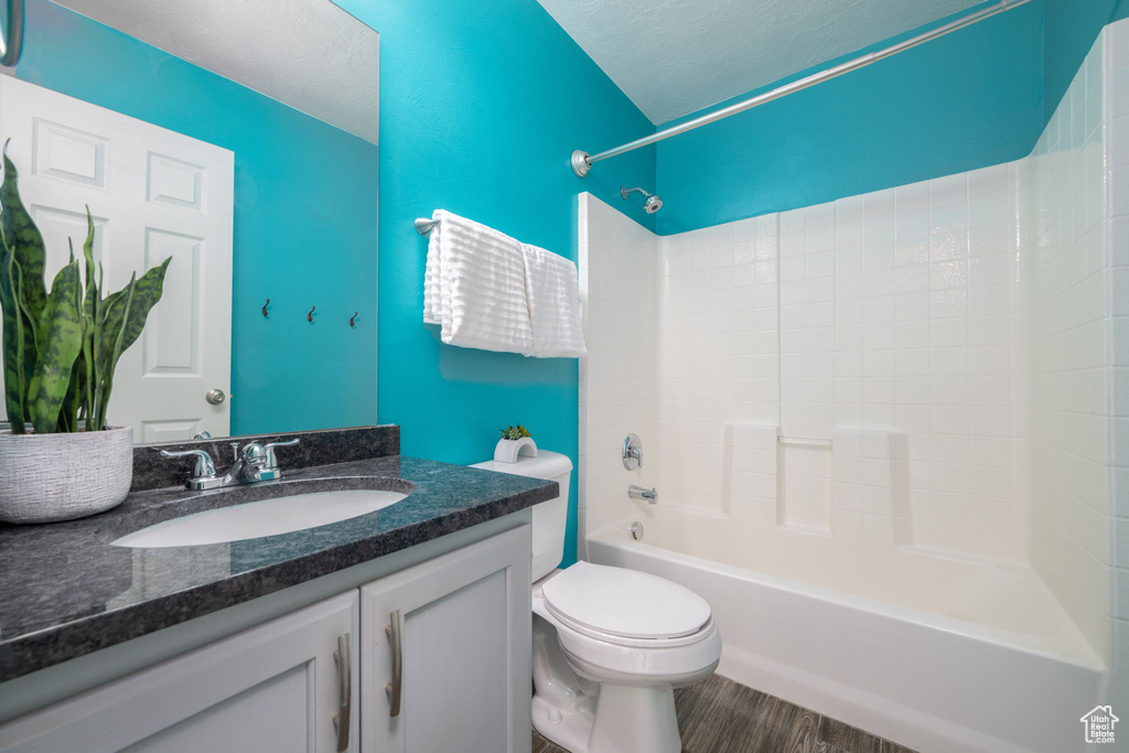 Full bathroom with shower / tub combination, vanity, and wood finished floors